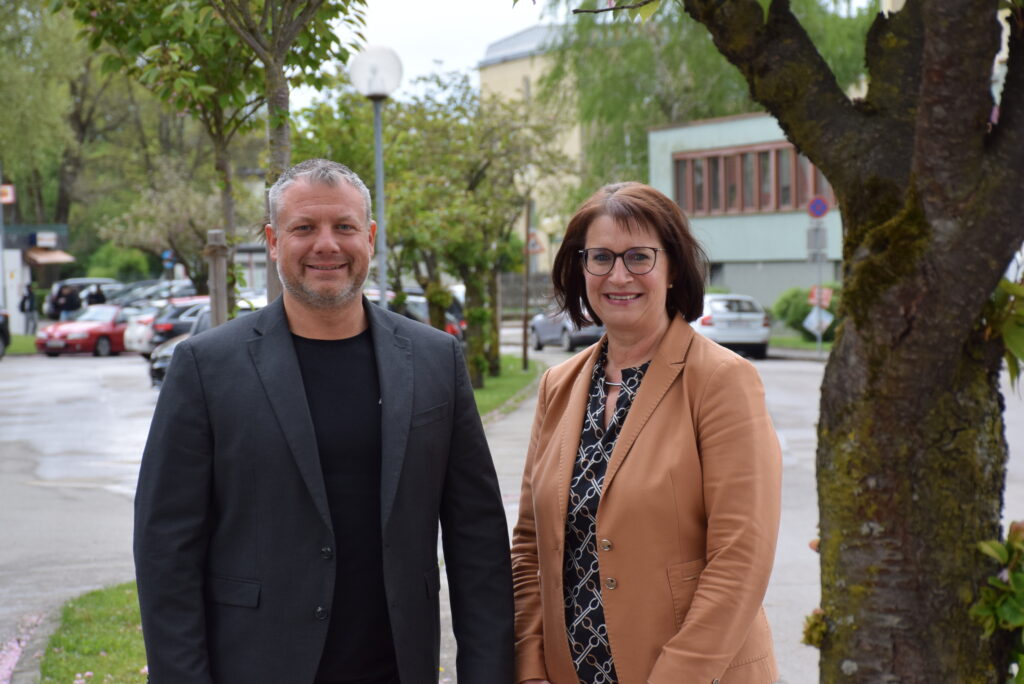 Vizebürgermeister Dominic Hörlezeder und Umweltgemeinderätin Michaela Pfaffeneder stehen zwischen Bäumen in der Nikolaus-Lenau-Straße.