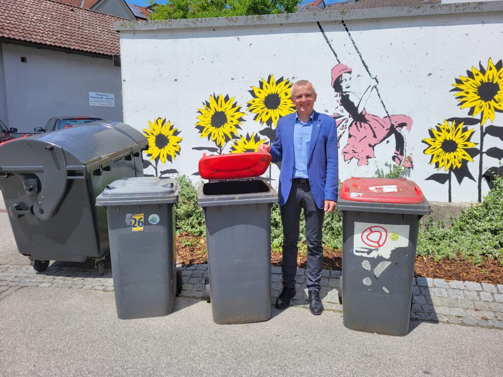 Finanzstadtrat Heinz Ettlinger steht zwischen mehreren Müllcontainern