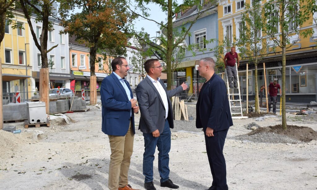 Vizebürgermeister Markus Brandstetter, Bürgermeister Christian Haberhauer und Vizebürgermeister Dominic Hörlezeder führen am Hauptplatz vor den neugepflanzten Bäumen ein Gespräch